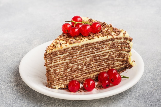 Pastel de panqueques de chocolate fino y crema de pistacho con grosellas rojas