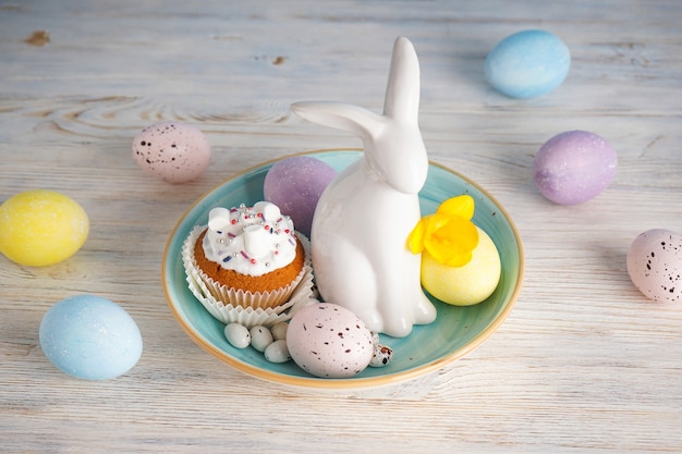 Pastel de Pascua, conejito de Pascua y huevos con flores sobre un fondo de madera.