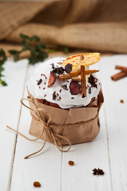 Pastel de Pascua decorado con frutos secos y palitos de canela sobre fondo de madera blanca, Kulich tradicional, Paska listo para la celebración