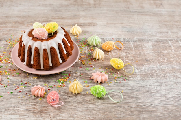 Pastel de pascua glaseado decorado con mini huevos dulces en mesa de madera Felices vacaciones de Pascua Espacio de copia