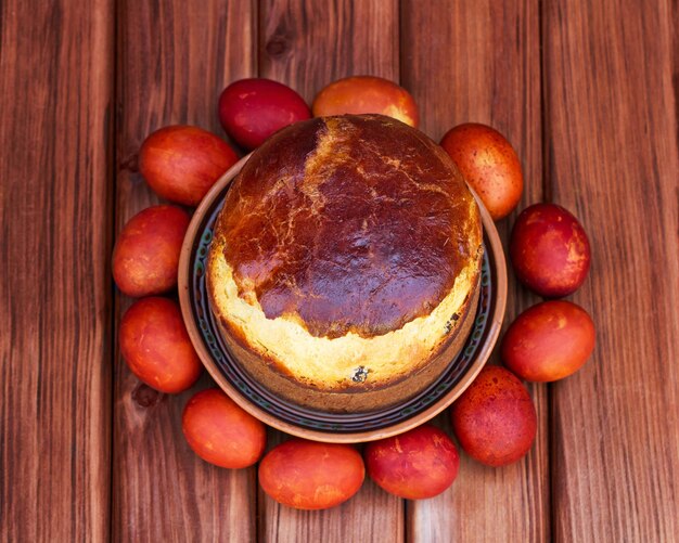 Pastel de pascua y huevos de colores en mesa de madera