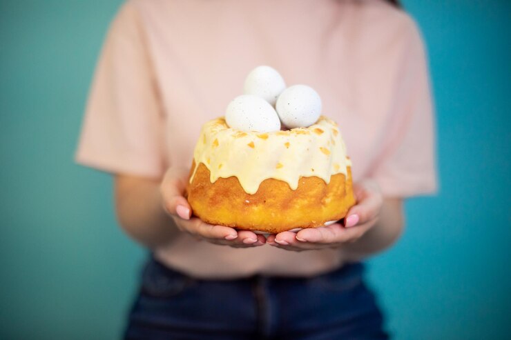 Pastel de Pascua con huevos en las manos sobre fondo azul Torta de embudo de Pascua tradicional babka polaca