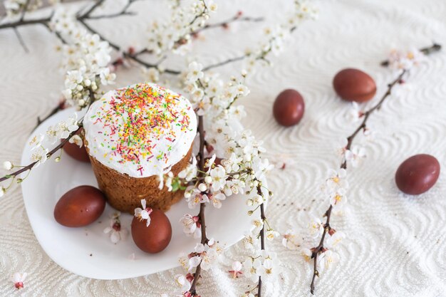 Pastel de Pascua y huevos pintados. Ramo floreciente sobre la mesa cerca.