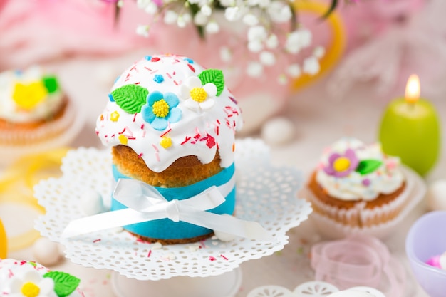 Pastel de Pascua tradicional con glaseado blanco, flores de azúcar y huevos coloridos.