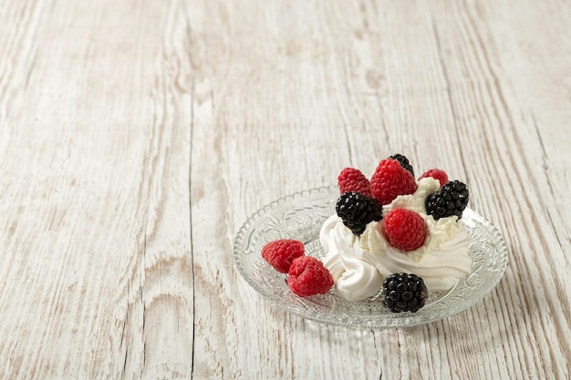 Pastel de Pavlova en una placa de vidrio. Fondo de madera.