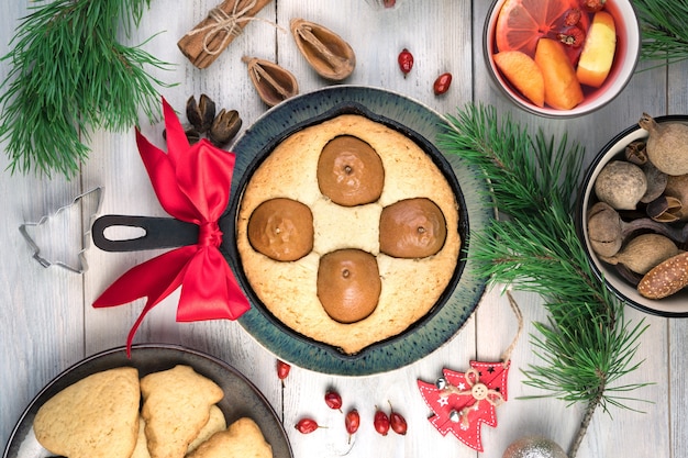 Pastel de pera y galletas sobre fondo de Navidad