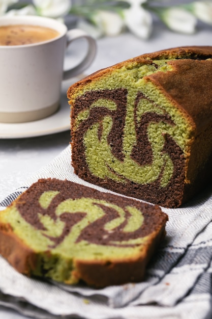 Pastel de pistacho de chocolate de mármol casero en rodajas en forma de pan sobre una toalla con una taza de café