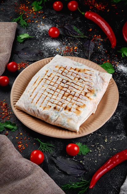 Pastel de pita shawarma relleno de carne de pollo y hierbas en una mesa de piedra oscura Concepto de restaurante de comida rápida y entrega Bollo cubierto