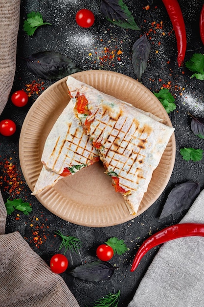 Pastel de pita shawarma relleno de carne de pollo y hierbas en una mesa de piedra oscura Concepto de restaurante de comida rápida y entrega Bollo cubierto