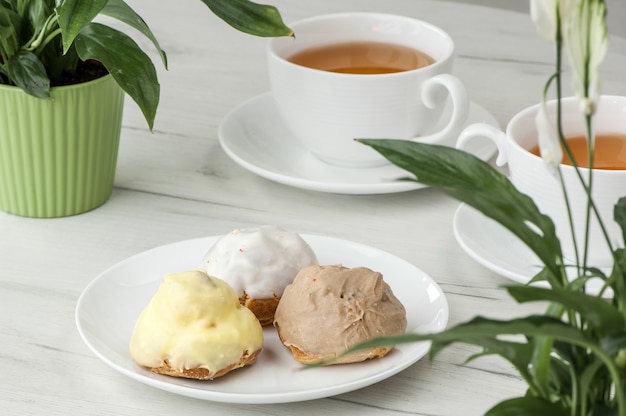 Pastel en un plato y dos tazas de té sobre la mesa con flores.