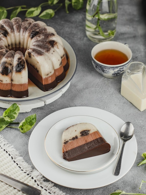 Pastel de pudín de chocolate servido en un plato con un vaso de té caliente