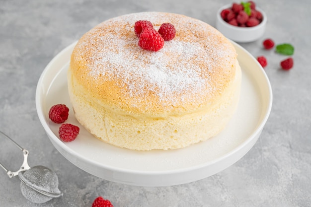 Pastel de queso de algodón japonés sobre un fondo de hormigón gris con frambuesas frescas y azúcar en polvo