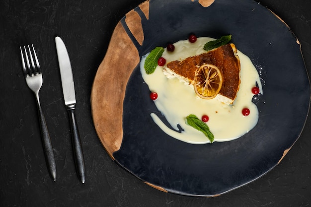 Pastel de queso clásico sobre un postre de fondo negro sobre un fondo negro en un plato negro