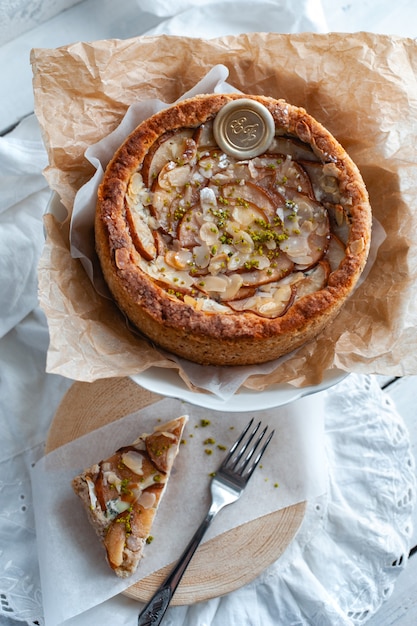 Foto pastel con queso dor blue, peras y almendras, todo redondo en un plato sobre una mesa blanca