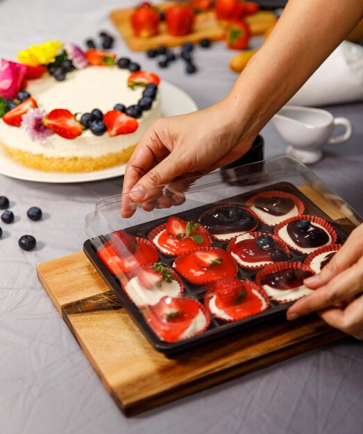 Pastel de queso dulce mini decorado con bayas frescas y flores en un plato de madera, para cumpleaños, día de San Valentín y celebración