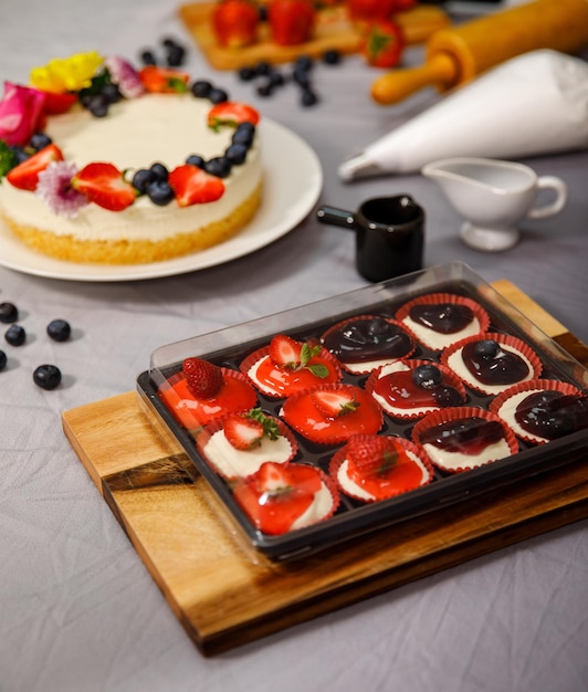 Pastel de queso dulce mini decorado con bayas frescas y flores en un plato de madera, para cumpleaños, día de San Valentín y celebración