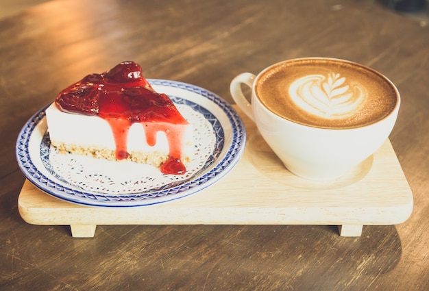 pastel de queso de fresa y café con leche en la mesa de madera