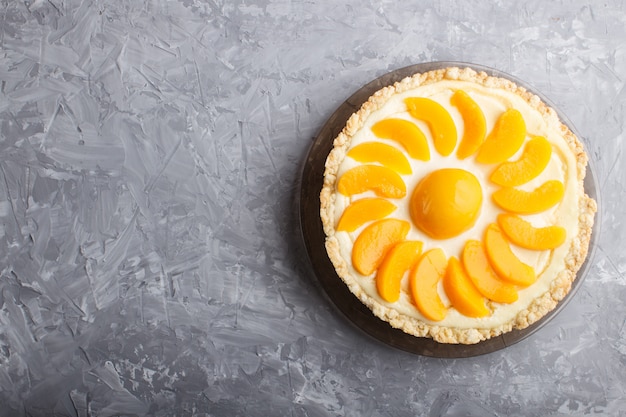 Pastel de queso del melocotón en un fondo concreto gris.