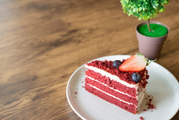 Pastel de queso rojo del terciopelo en la tabla de madera en café.