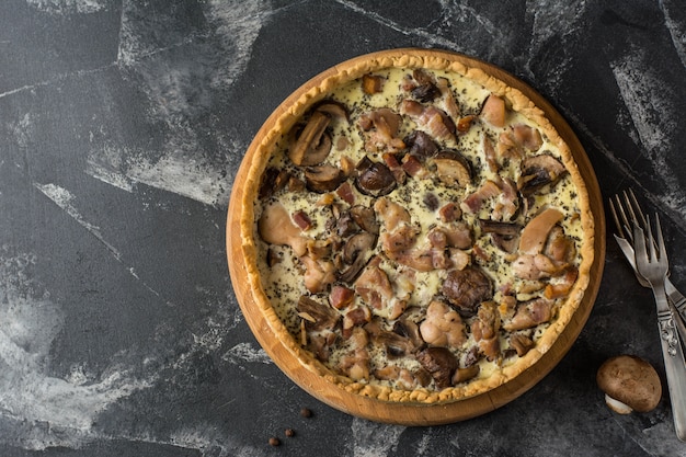 Pastel de quiche de champiñones con champiñones y queso sobre fondo oscuro