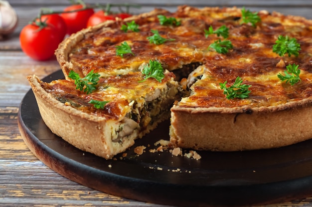 Pastel de quiche francés tradicional con pollo y champiñones sobre un fondo de madera