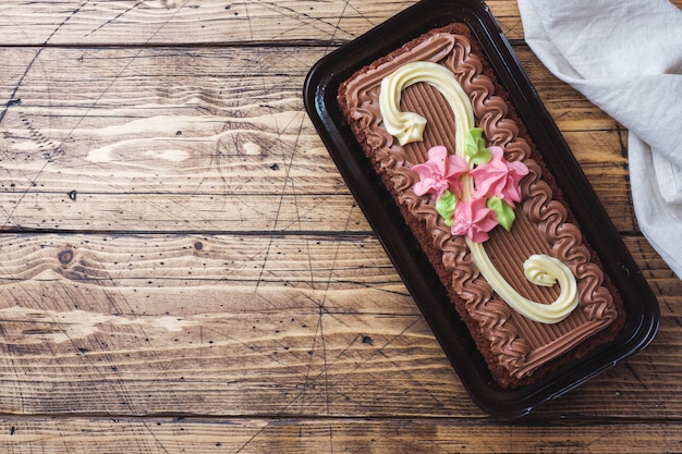 Pastel rectangular de chocolate decorado con rosas crema.