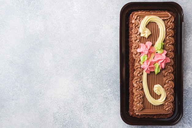 Pastel rectangular de chocolate decorado con rosas crema.