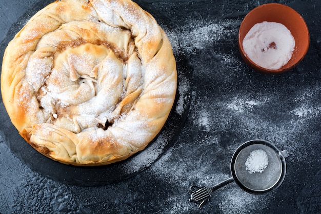 Pastel redondo de burek con una manzana sobre un fondo oscuro. Cocina tradicional serbia. Enfoque selectivo. Vista superior.