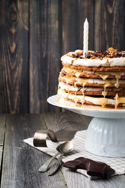 Pastel de repostería en capas caseras y merengue, nueces, chocolate negro sobre madera vieja