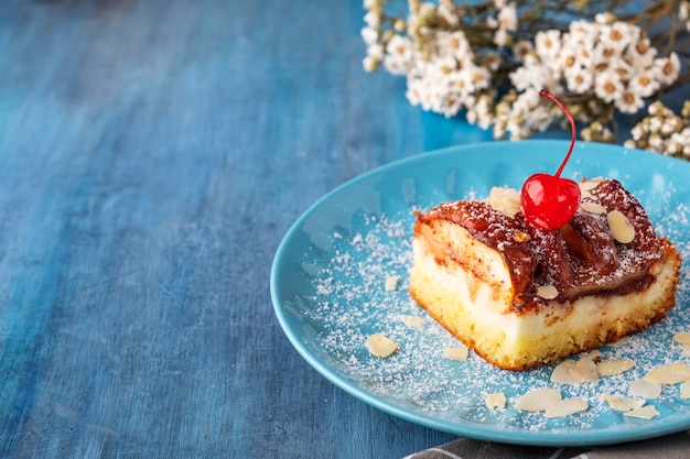 Pastel de requesón y manzanas acompañado de hojuelas de almendra y cereza de cóctel. Copie el espacio.