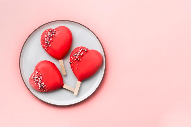 Pastel rojo aparece paletas en plato blanco Corazones rojos Amor y dulce concepto Día de San Valentín