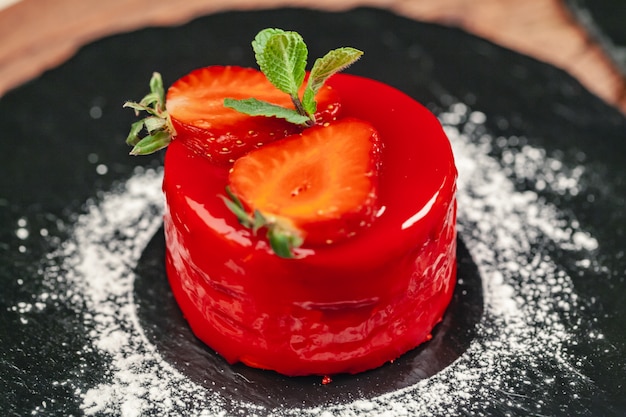 Pastel rojo con crema en plato blanco sobre mesa de madera