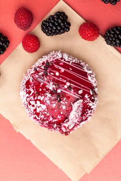 Un pastel rojo con un relleno blanco cremoso, mermelada roja con frambuesas y moras