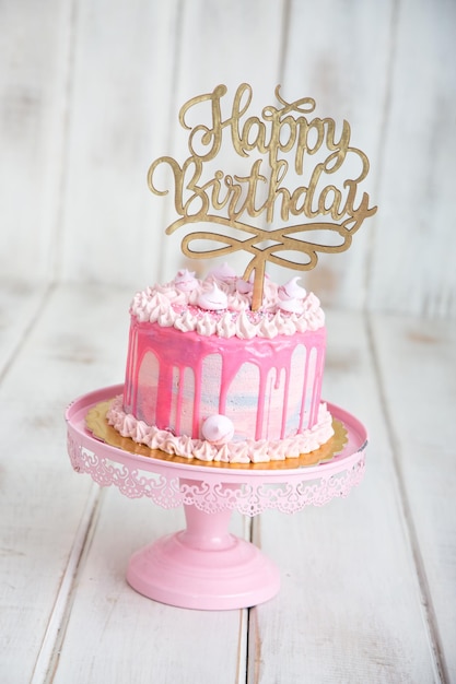 Un pastel rosa con feliz cumpleaños escrito en él