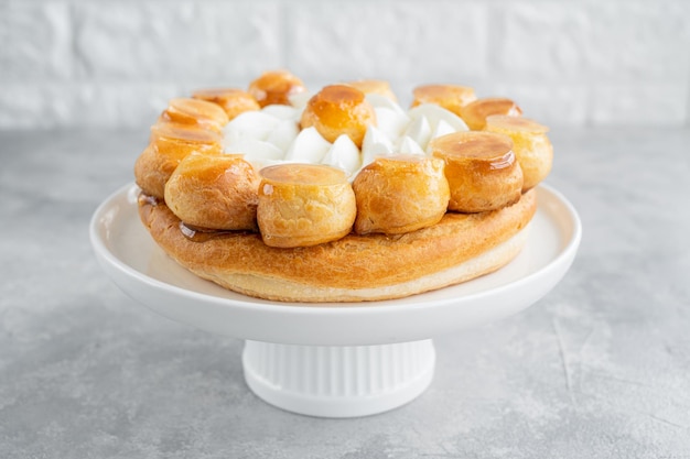 Pastel de Saint Honore con flan de caramelo de profitrols y crema batida en un plato blanco Espacio de copia