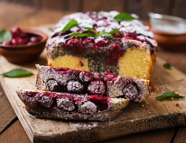 Pastel de semillas de amapola de cereza espolvoreado con azúcar en polvo sobre una mesa de madera