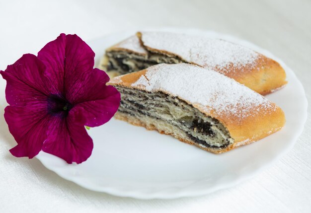 El pastel de semillas de amapola se encuentra en un plato decorado con una flor viva