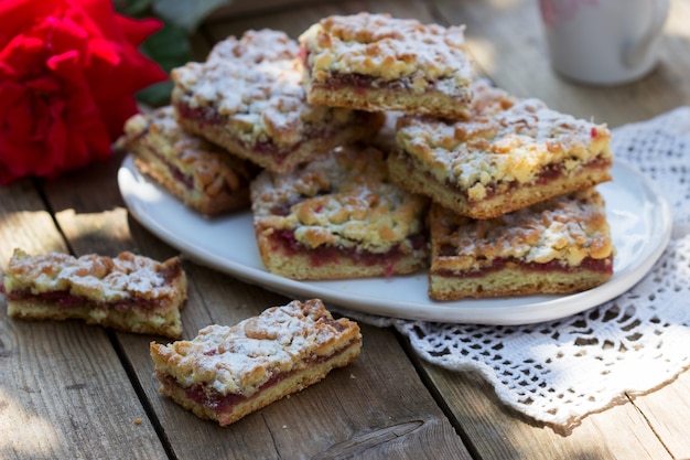 Pastel de Streusel relleno de mermelada de rosas, servido con café. Estilo rústico.