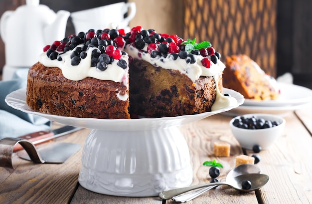 Pastel. Tarta navideña casera con frutos secos decorados con crema de vainilla dulce, bayas frescas y crema sobre un fondo de madera antiguo. Enfoque selectivo.