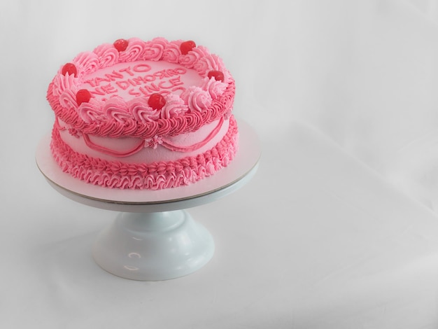 Pastel de taza de glaseado rosa con letras de texto en inglés italiano como aderezo para cumpleaños
