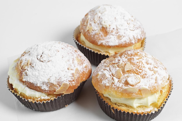 Pastel de té con crema batida y almendras sobre fondo blanco.