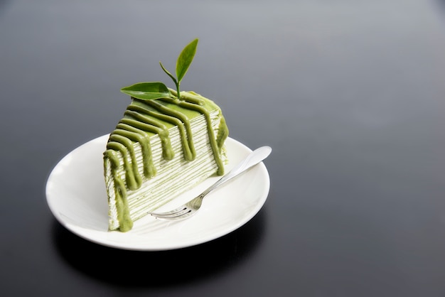 Pastel de té japonés Matcha Green con hojas de té en plato blanco