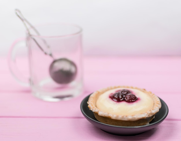 Pastel y té en un vaso sobre un fondo de madera rosa