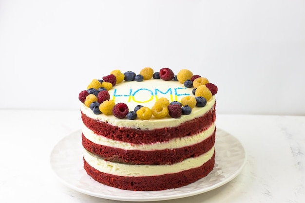 Pastel de terciopelo rojo con una decoración de frambuesas y arándanos amarillos y rojos Homecoming