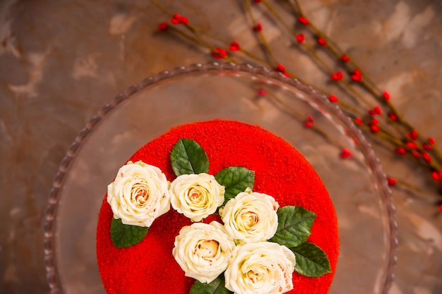 Pastel de terciopelo rojo decorado con pequeñas rosas blancas con hojas verdes.