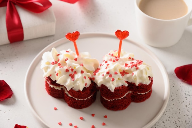 Pastel de terciopelo rojo en forma de corazones y café para el día de San Valentín sobre fondo blanco Postre sabroso Cerrar