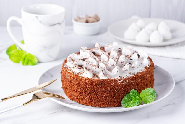 Pastel de tiramisú casero perfecto espolvoreado con cacao en polvo en un plato sobre una mesa de mármol blanco