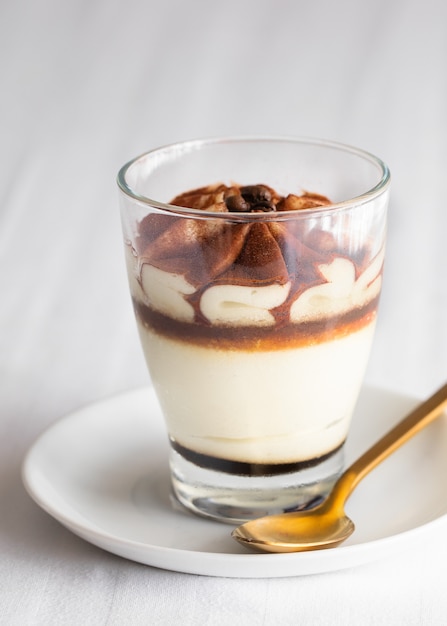 Pastel de tiramisú clásico en un vaso sobre fondo blanco. Pastel de postre de mascarpone en capas.