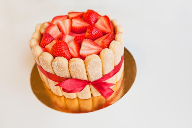 pastel de tiramisú con fresas bizcochos mascarpone y cinta de moño rojo aislado en blanco