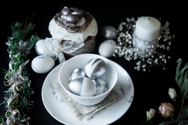 Pastel tradicional de Pascua con velas de huevos pintados de plata y sauce sobre un fondo negro Enfoque selectivo